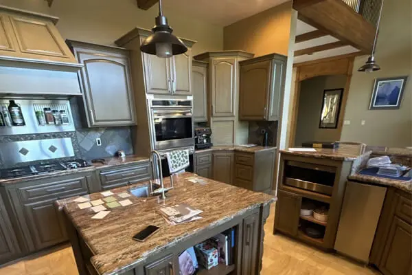 A bright, modern kitchen showcasing freshly painted gray cabinetry, warm wood-toned countertops, stainless steel appliances, and elegant pendant lighting, designed for a clean and functional cooking space.