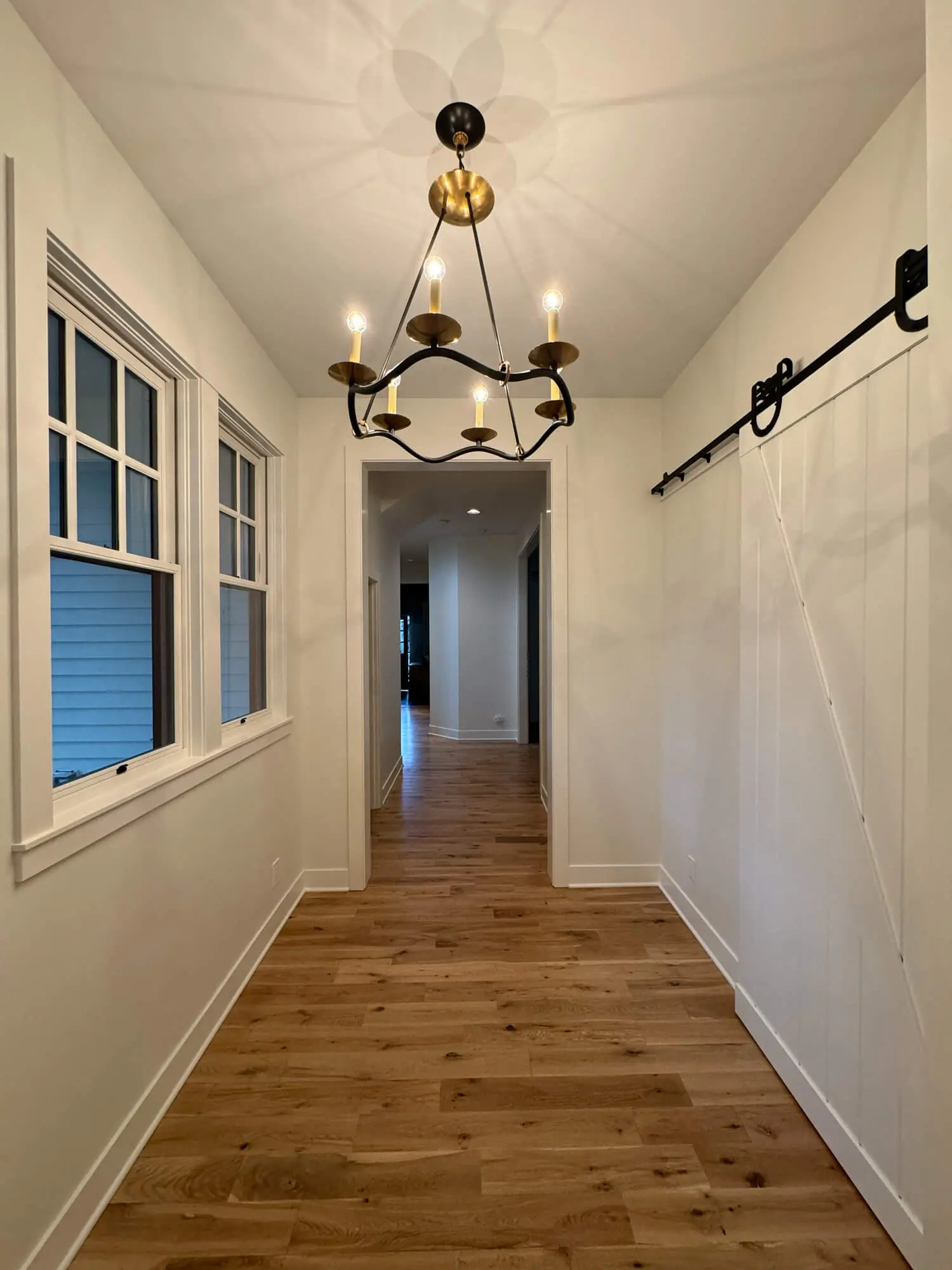 freshly painted white hallway with barn door and hardwood floors in Central Oregon home