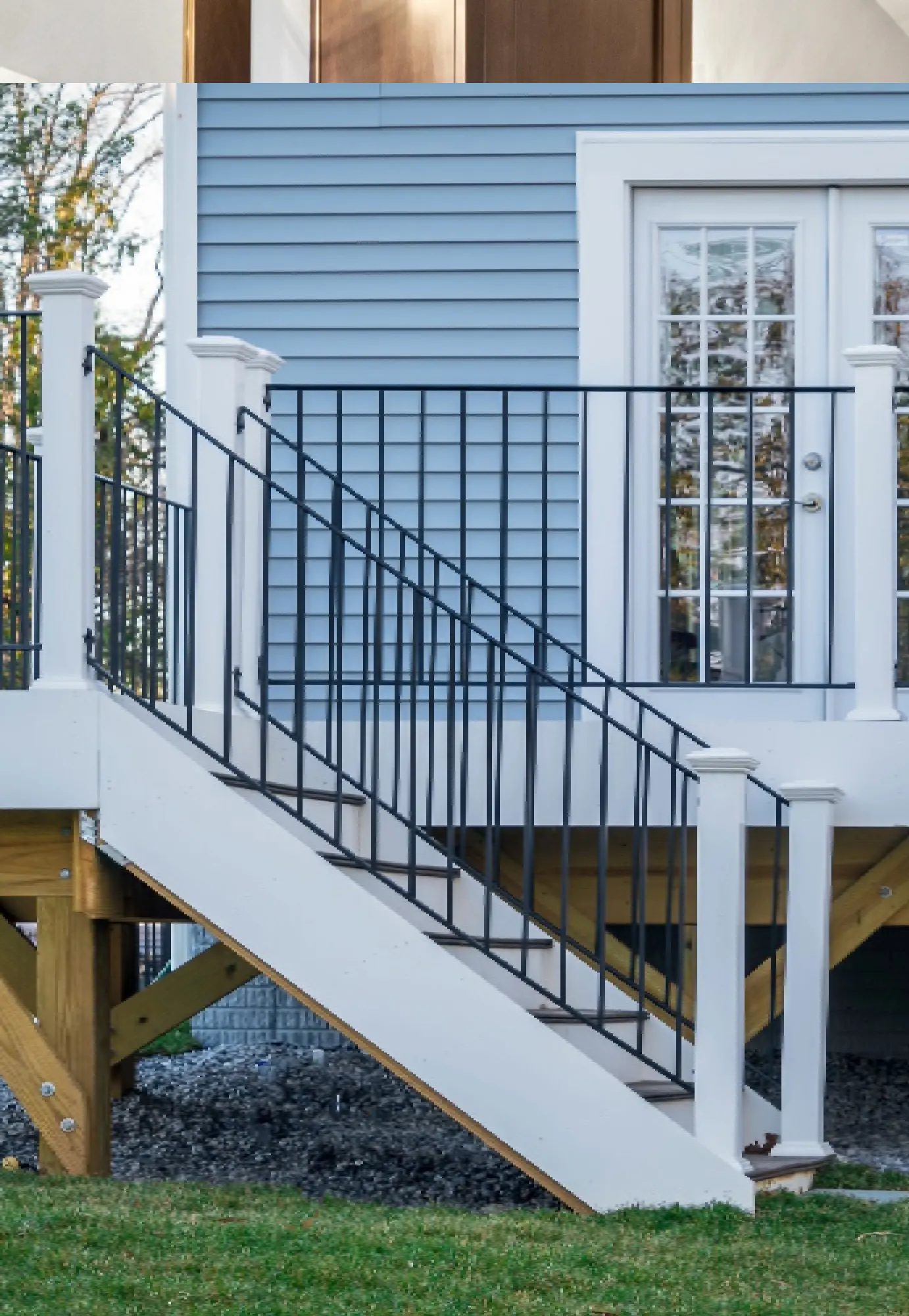 exterior shot of a residential home featuring a deck with new white vinyl railings and stairs, showcasing a completed project by West Rivers Painting in Bend, OR.