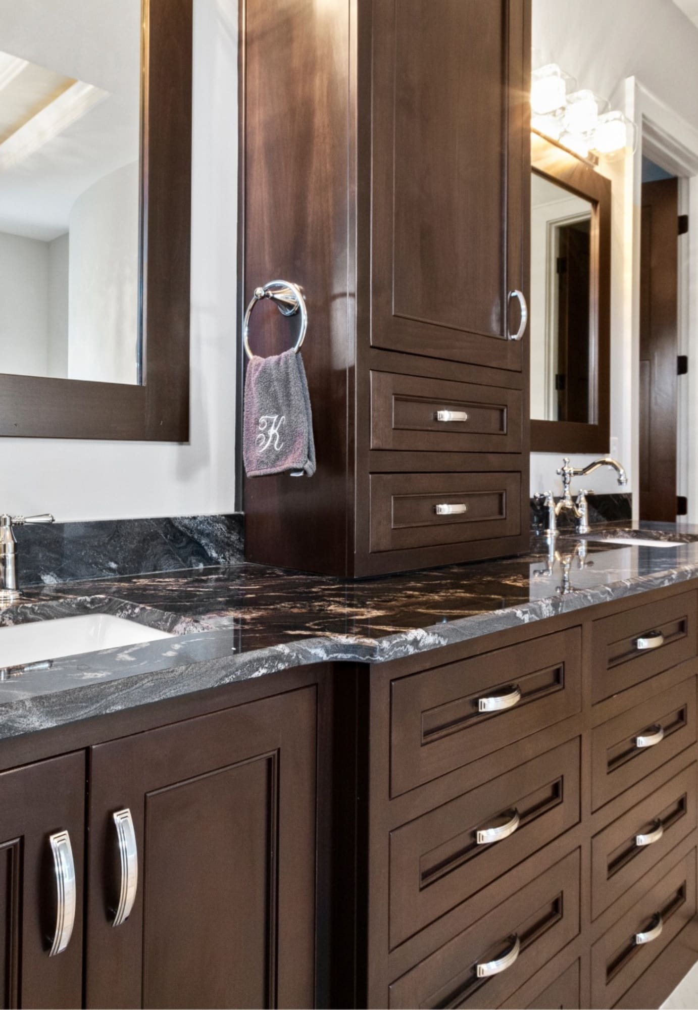 A professional interior view of a modern bathroom featuring dark-brown wood vanity cabinets with a granite countertop, a vessel sink, and a matching framed mirror, showcasing a high-quality finish by West Rivers Painting in Bend, OR.
